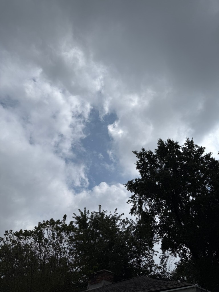 Broken gray cloud deck opening to a patch of blue sky in Raytown, Missouri at 2:04 PM on September 10, 2026.