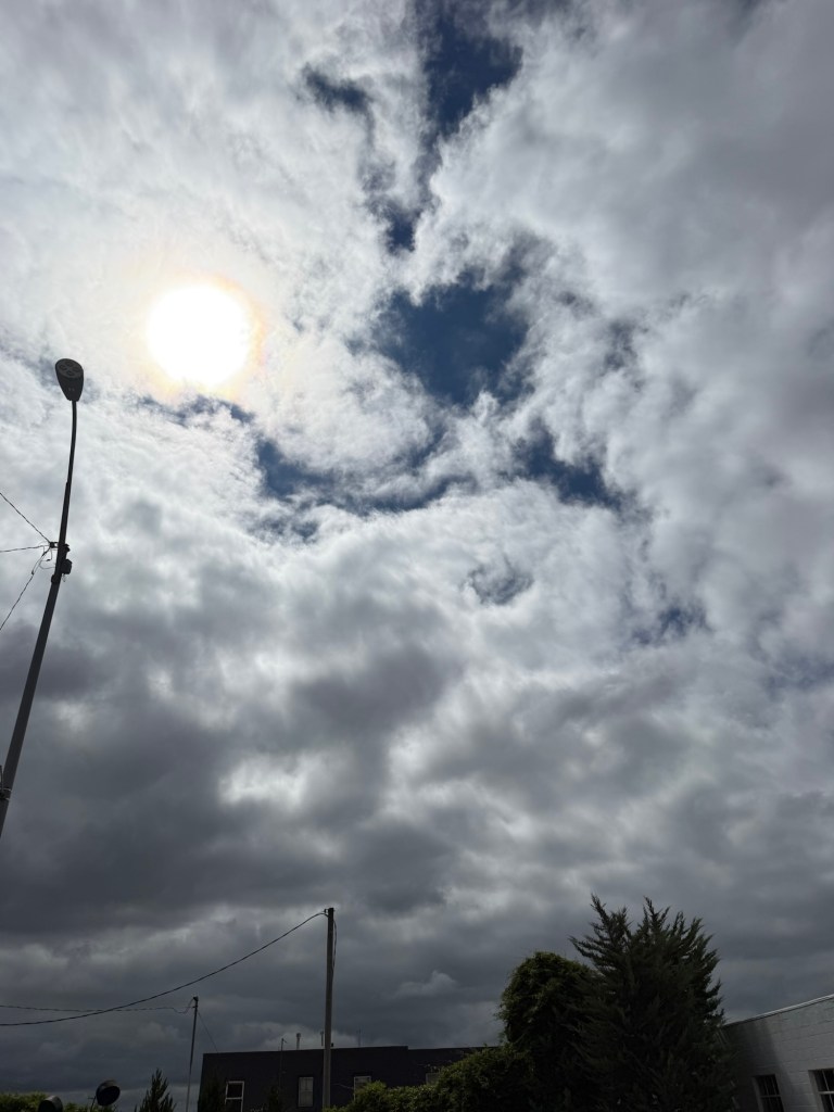 A vivid opening of blue between dark gray cloud layers
