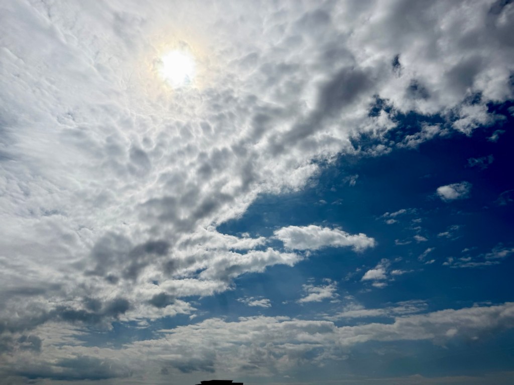 Textured white and gray clouds beside a large blue opening over Lenexa, Kansas