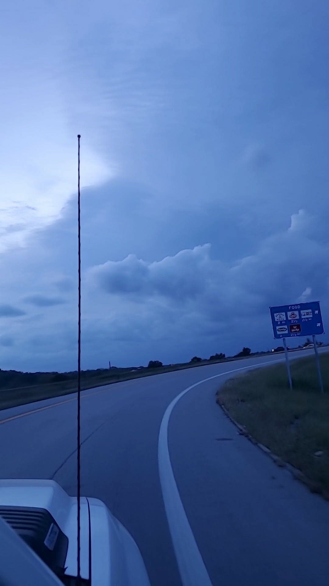 Rounded cloud bank beside a curving highway ramp under blue-gray skies