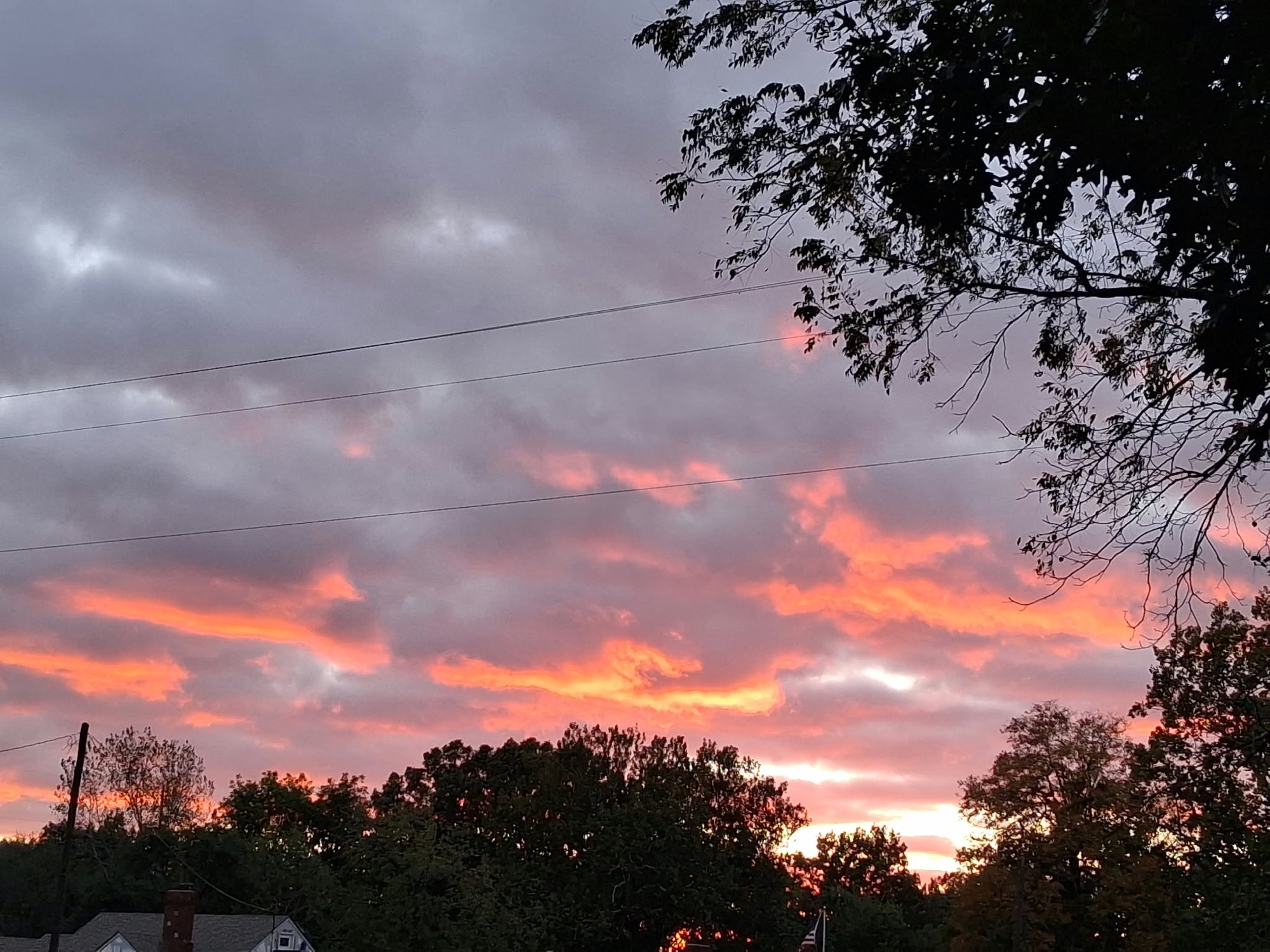 Coral pink and orange sunset illuminating layered clouds over Independence Missouri
