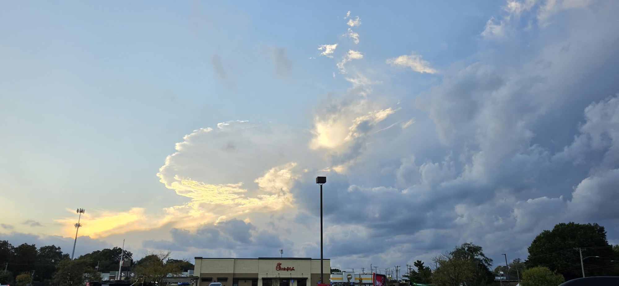 Wispy sunlit cloud streaks above billowing gray clouds