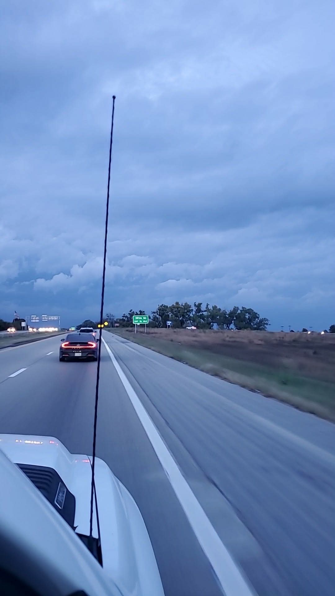 Layered blue-gray clouds over a highway and passing vehicles