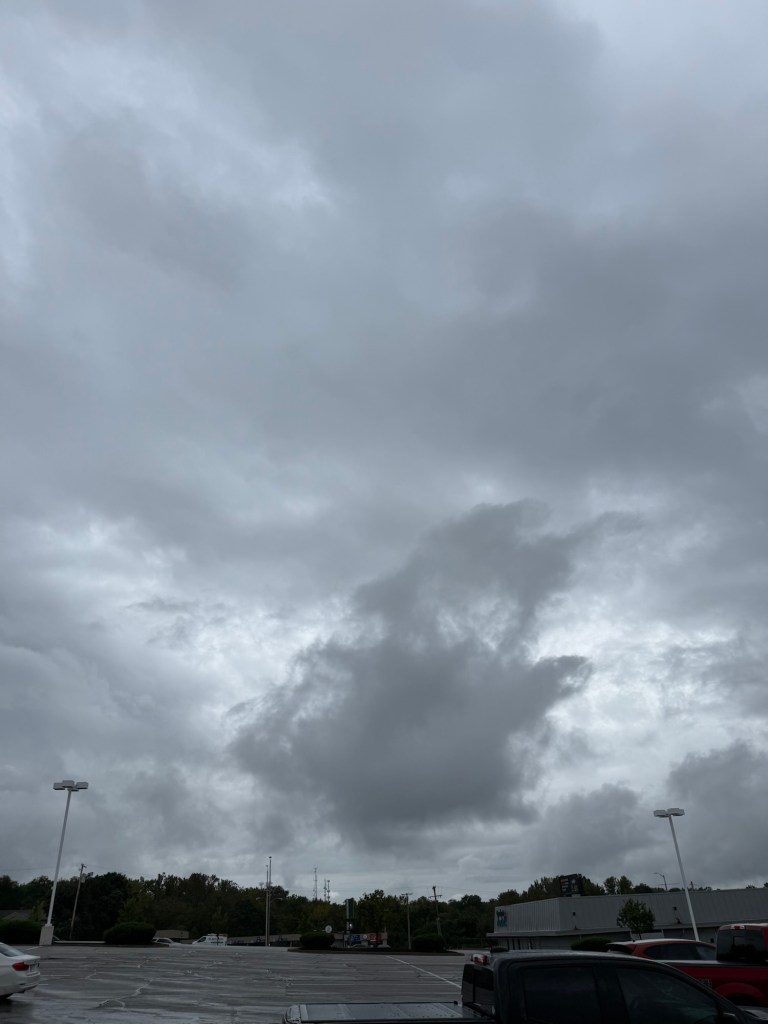 Large dark isolated cloud mass beneath a gray overcast deck in Raytown