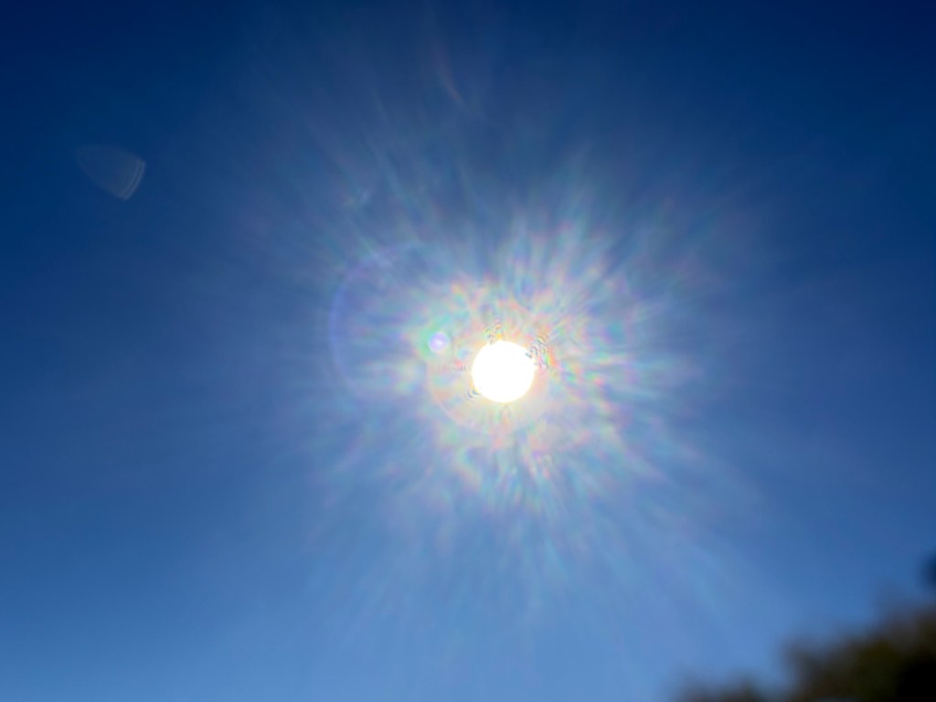 Unfiltered photograph of the bright afternoon Sun producing a colorful camera optical effect