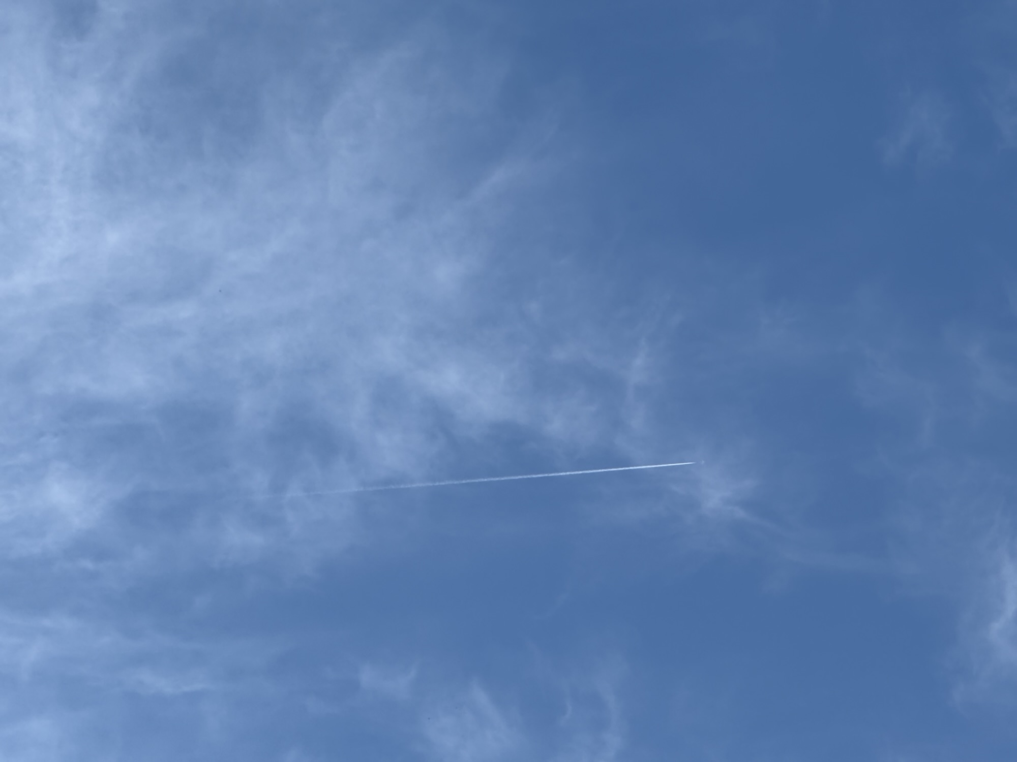 White airplane contrails crossing against clear blue sky.
