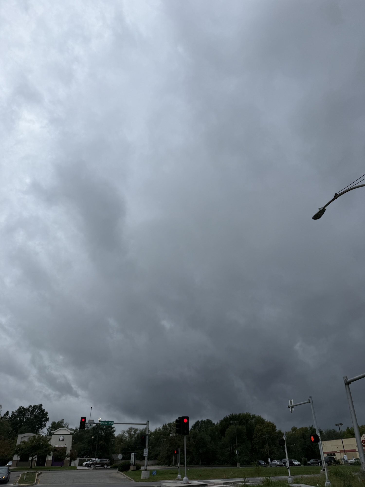 Layers of gray rain clouds over businesses and trees in Raytown