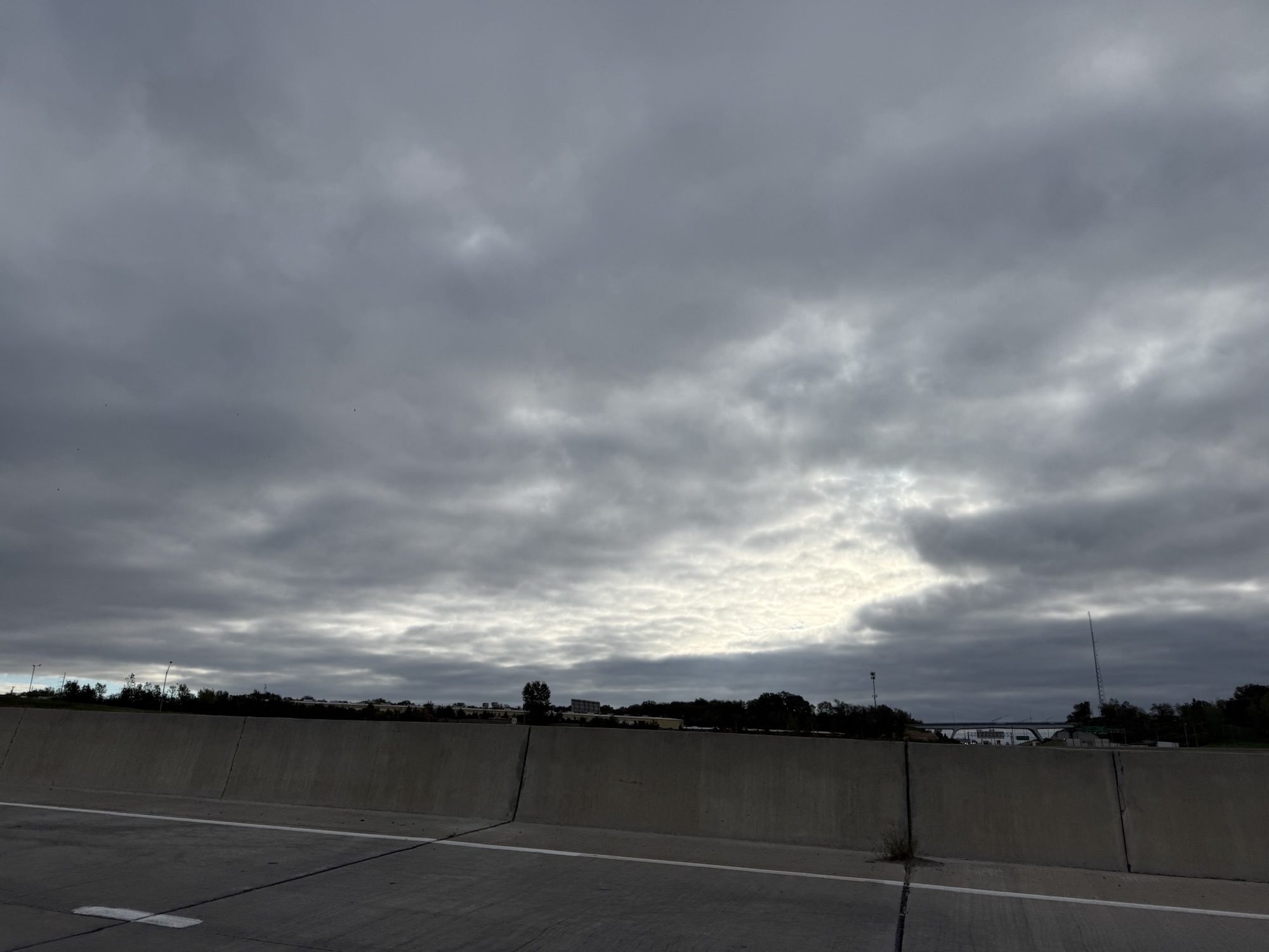 Gray morning clouds above highway barrier