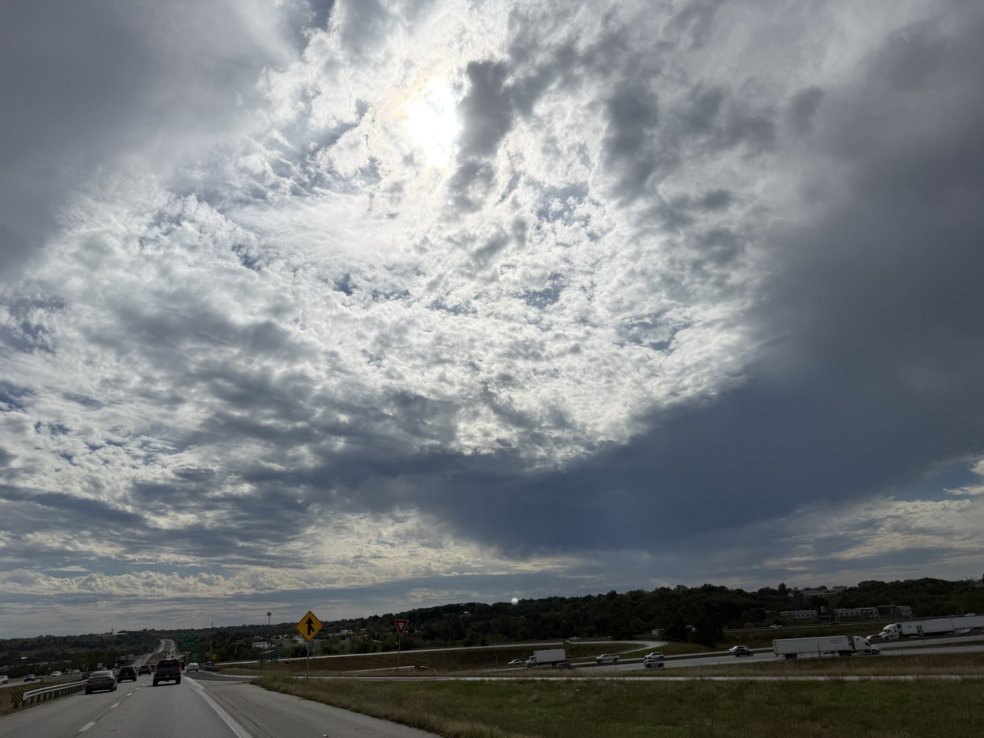 1:52 PM, Kansas City area: sunlight above a dark cloud bank and roadway.
